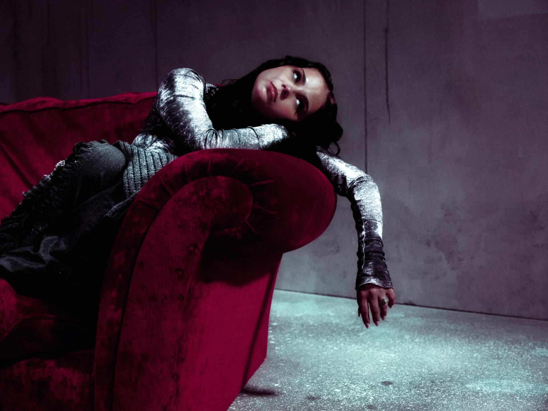 Sabyna reclining on a crimson velvet sofa