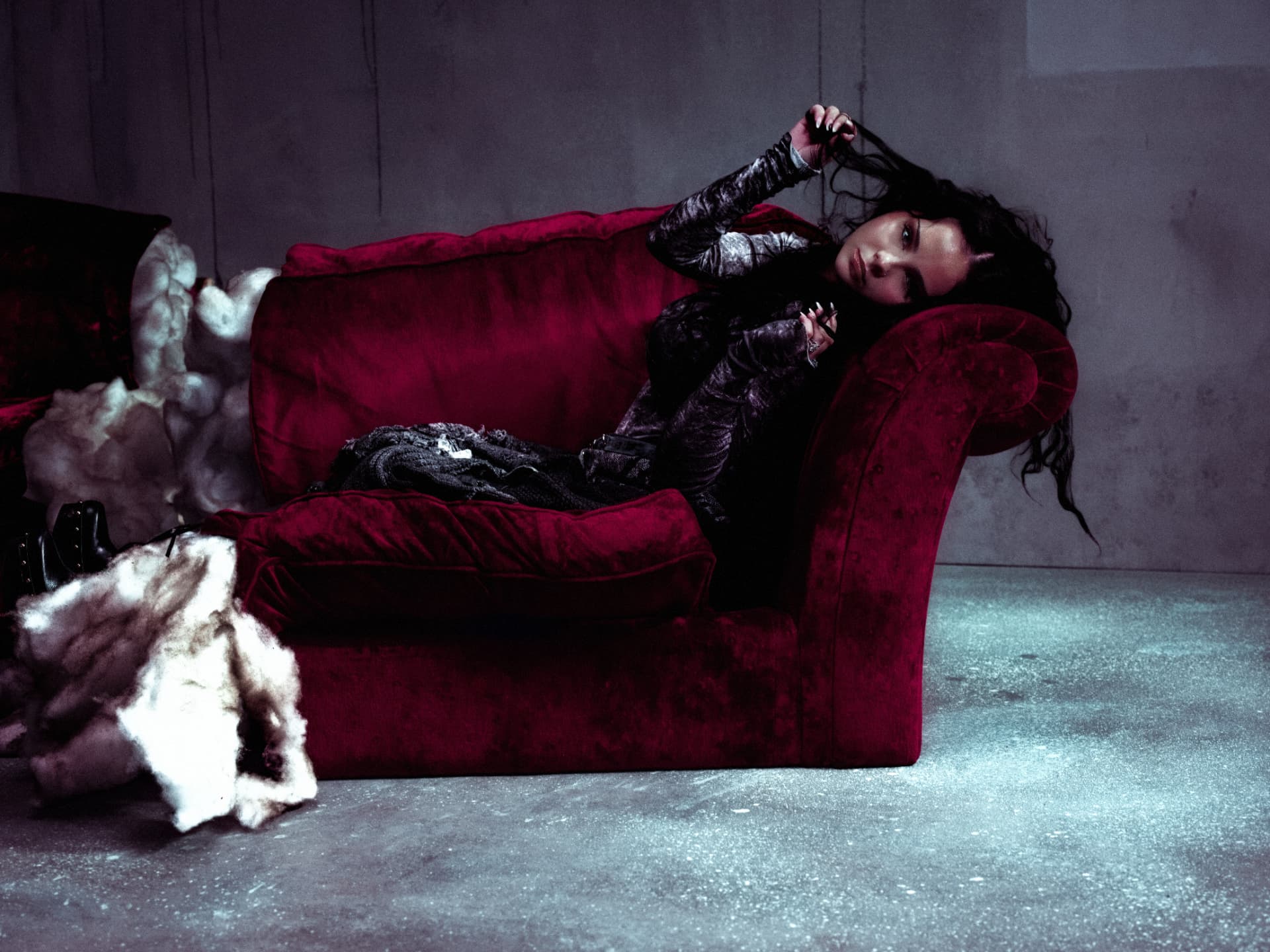 Sabyna seated on a crimson velvet sofa