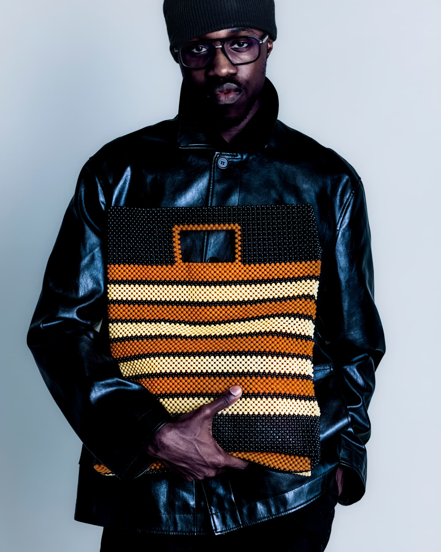 Close study of a striped beaded bag held against leather