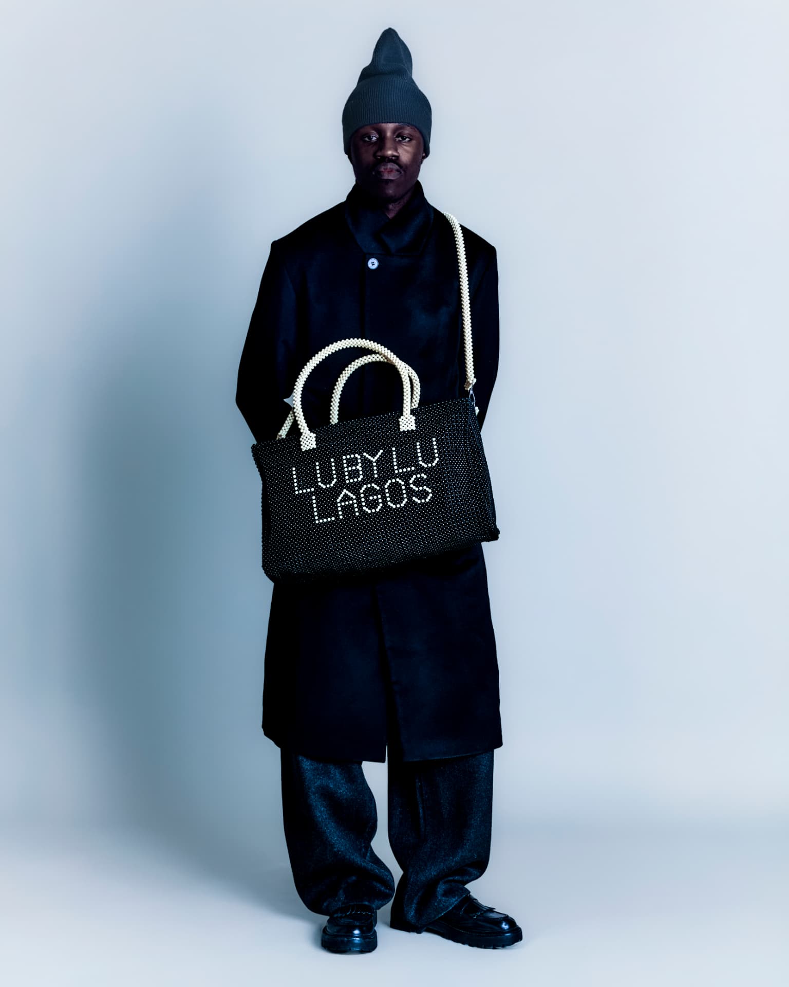 Model in black tailoring with a beaded LU BY LU Lagos tote