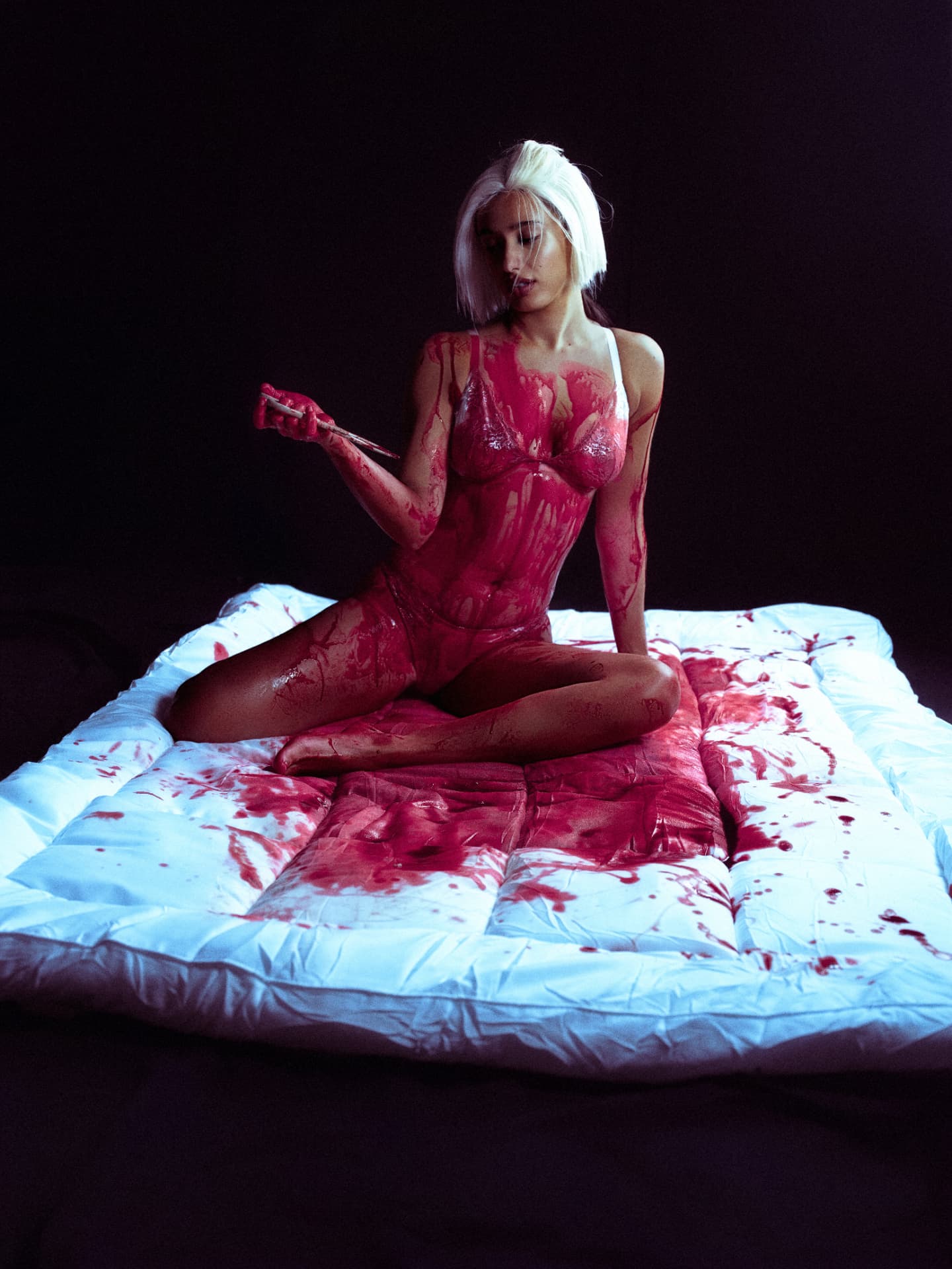 Delilah seated in crimson holding a brush